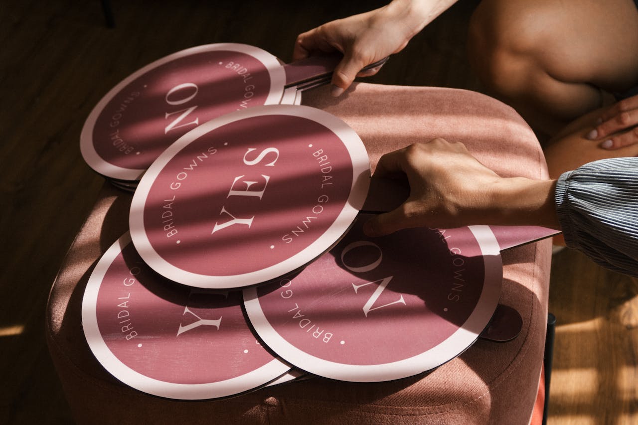 Close-up of hands holding pink bridal gown 'yes' and 'no' signs on a stool.